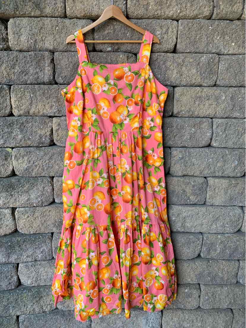 Sleeveless midi dress with orange and yellow floral print on bright coral background.