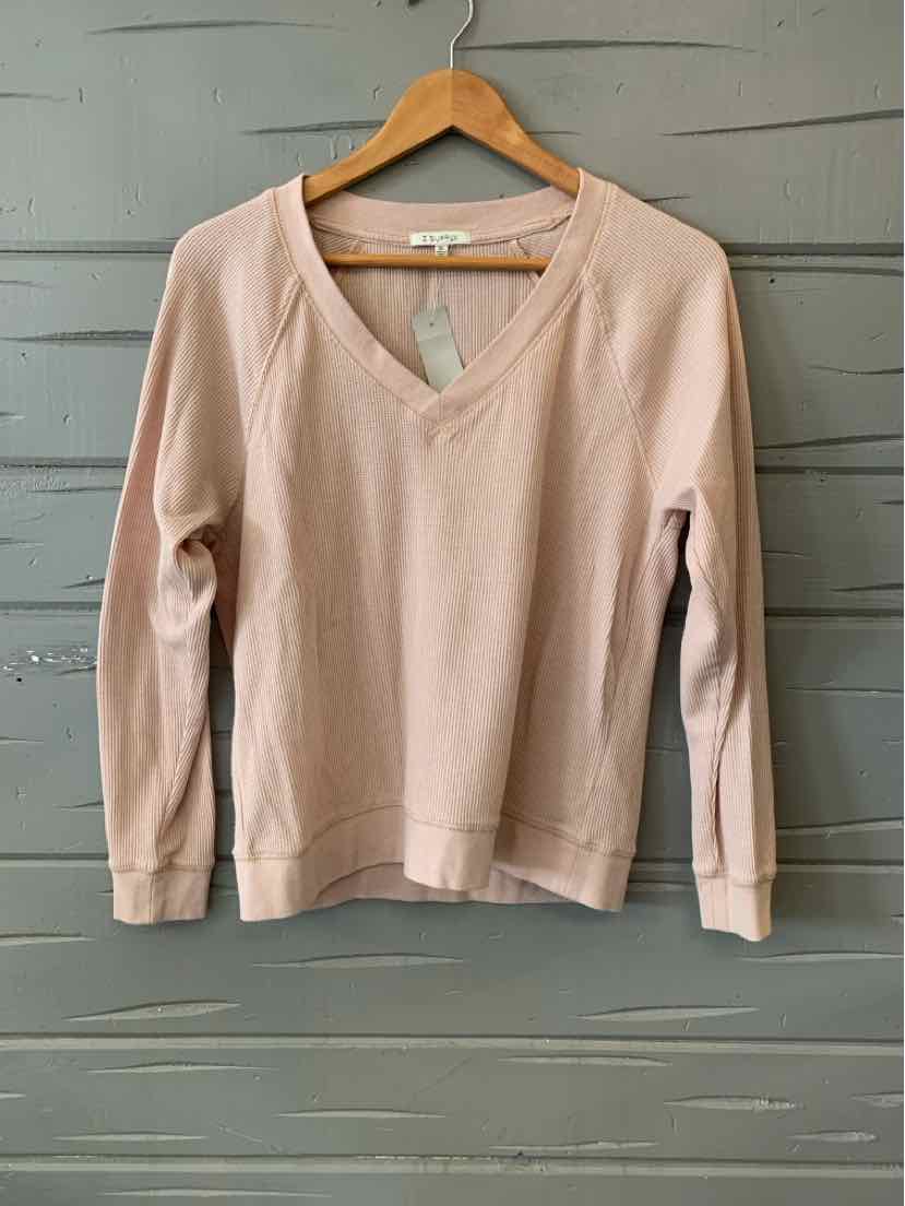 Light pink waffle-knit long-sleeve V-neck top with ribbed cuffs, hanging on wooden hanger.