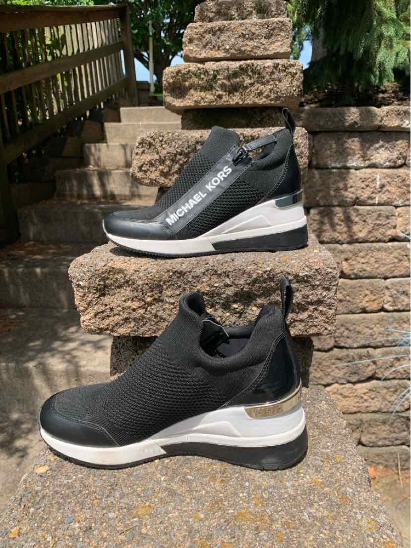 Black slip-on sneaker with white sole and knit upper, sleek athletic design, size 6.