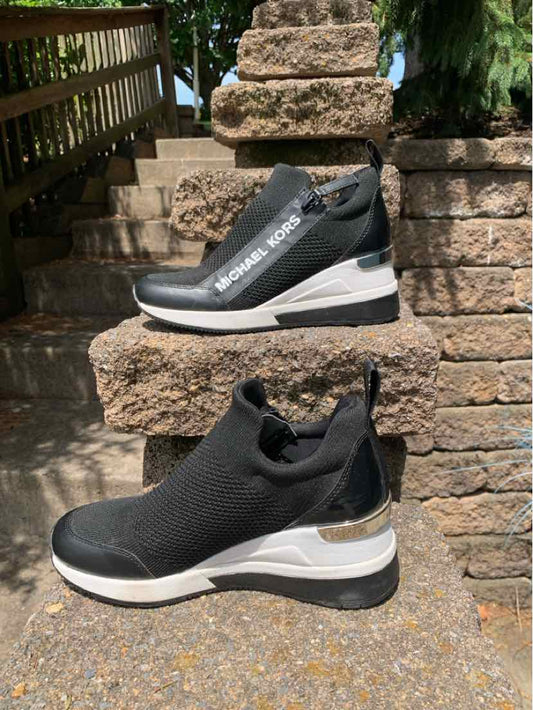 Black slip-on sneaker with white sole and knit upper, sleek athletic design, size 6.