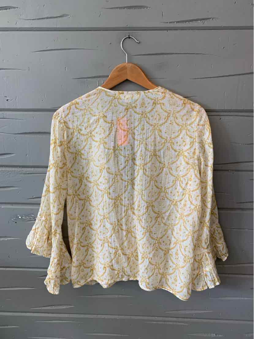 Light cream blouse with yellow paisley print, long bell sleeves, and loose fit on wooden hanger.