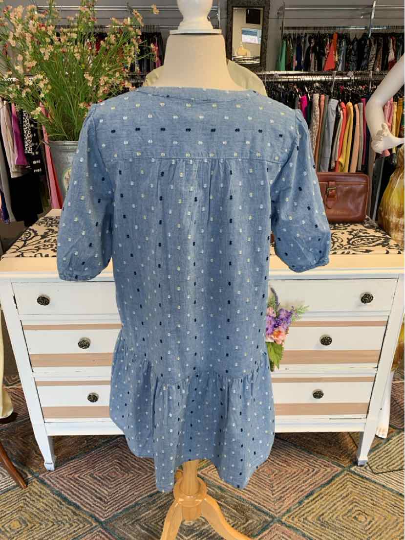 Blue short-sleeve dress with white polka dots and ruffled hem on mannequin.
