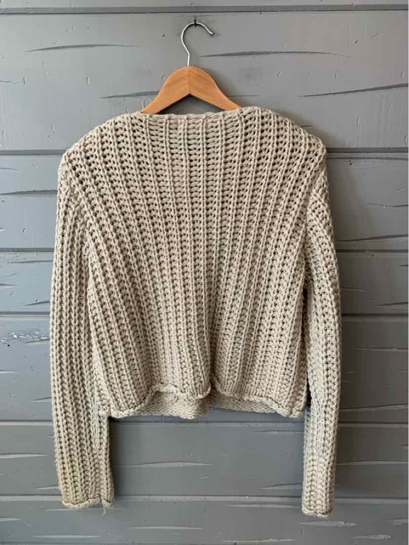 Taupe chunky knit sweater with long sleeves and a cropped hem on wooden hanger.