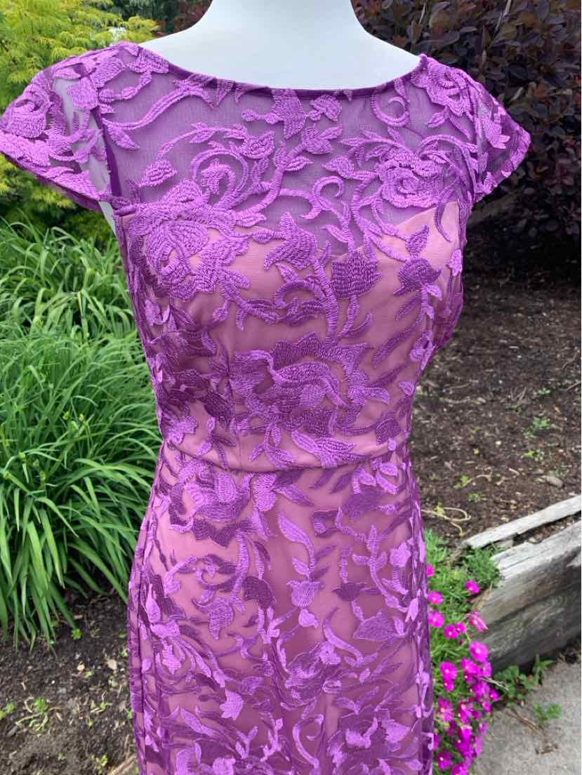 Lavender lace cocktail dress with cap sleeves and fitted waist on mannequin outdoors.