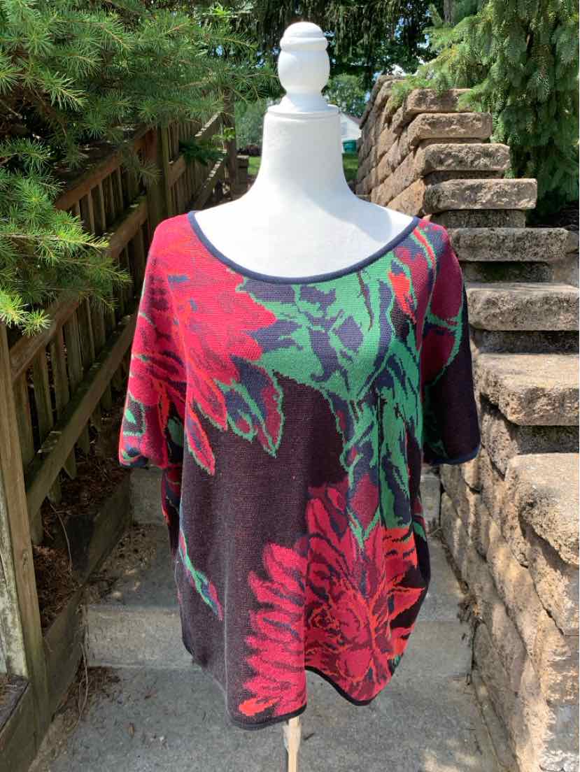 Loose-fitting burgundy sweater with large green and red floral pattern and wide neckline.