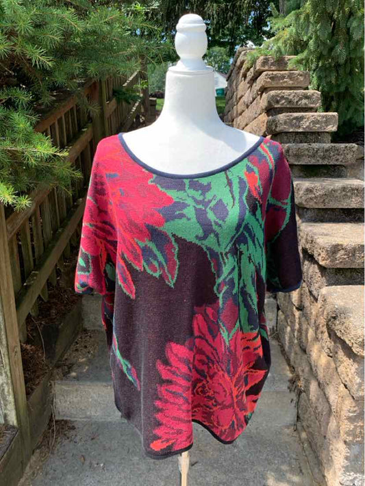 Loose-fitting burgundy sweater with large green and red floral pattern and wide neckline.