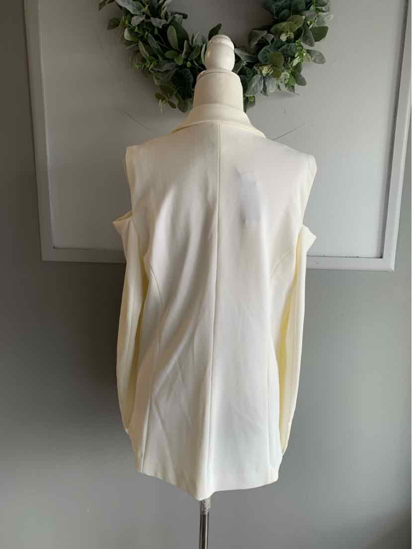 Cream sleeveless blouse with structured shoulders on mannequin against gray wall.