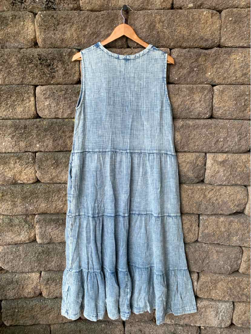 Light blue chambray sleeveless midi dress with tiered ruffle hem on wooden hanger.