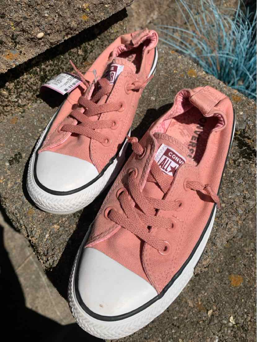 Womens Converse low-top sneakers in dusty pink canvas with white rubber toe caps and black trim detailing.