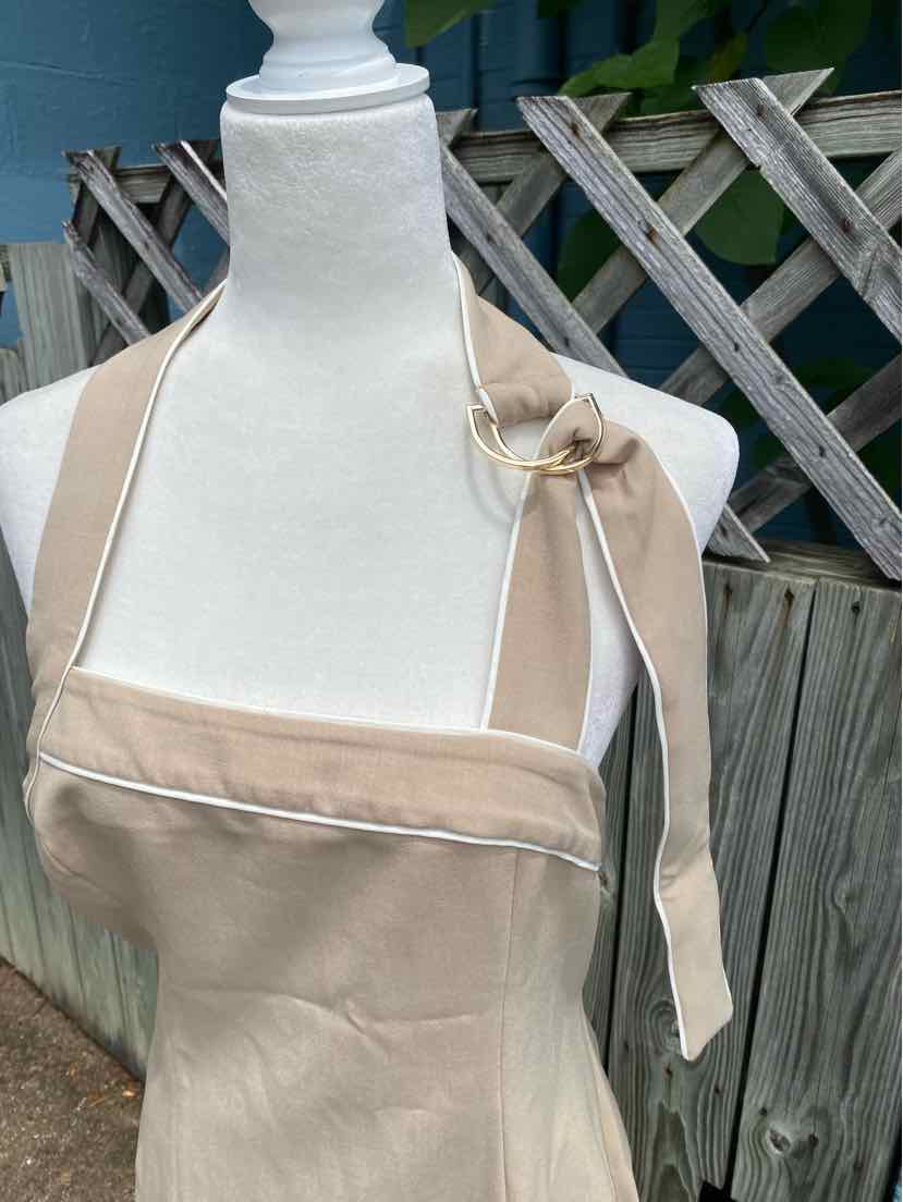 Tan solid fabric apron with halter neck tie and gathered detail on bust.