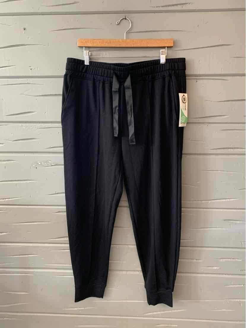 Black tapered jogger pants with elastic waistband and drawstring, size XL, hanging on wooden hanger.