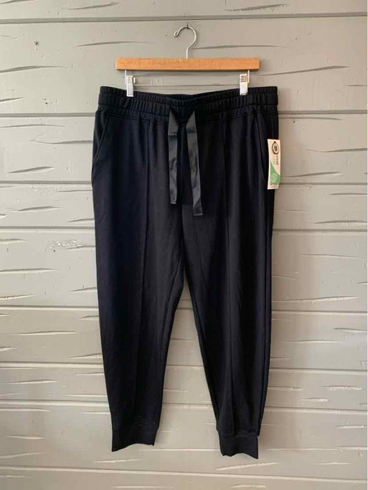 Black tapered jogger pants with elastic waistband and drawstring, size XL, hanging on wooden hanger.