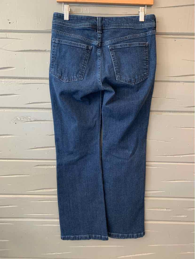 Dark blue denim jeans with straight legs and two back pockets hanging on a wooden hanger against a gray wooden background.