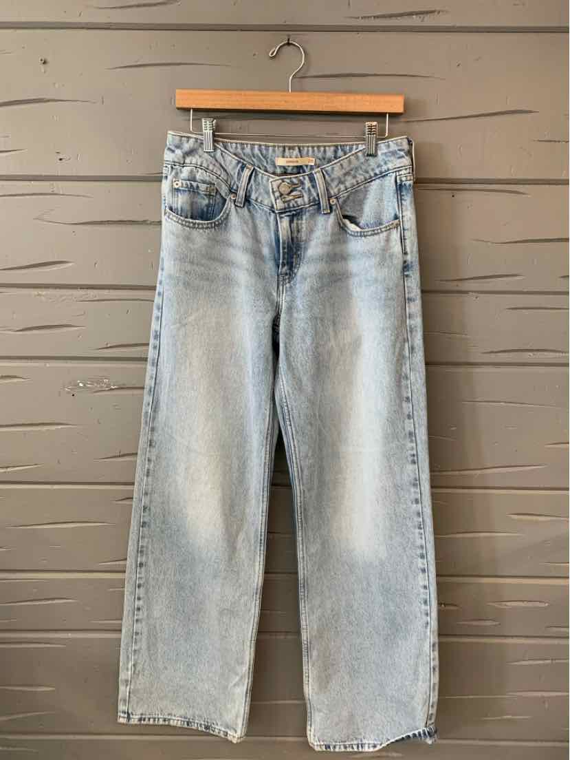 Light blue high-waisted Levi's denim jeans with straight legs and classic five-pocket design hanging on wooden hanger.