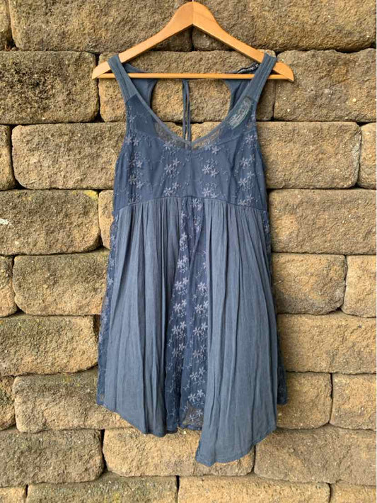 Blue sleeveless dress with floral embroidery and pleated skirt hanging on wooden hanger.