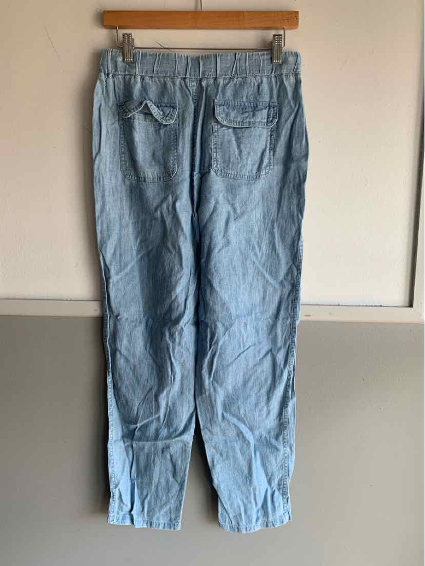 Light blue denim pants with elastic waistband and two back pockets hanging on wooden hanger.