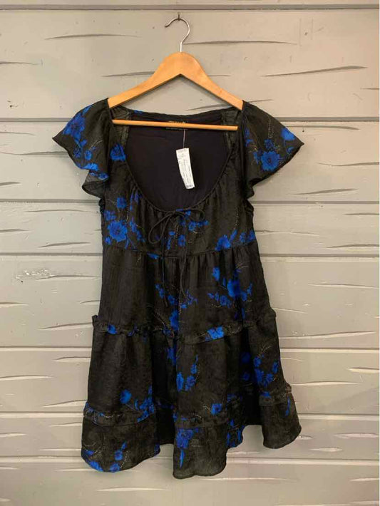 Black short-sleeve dress with blue floral print and ruffled hem on wooden hanger.
