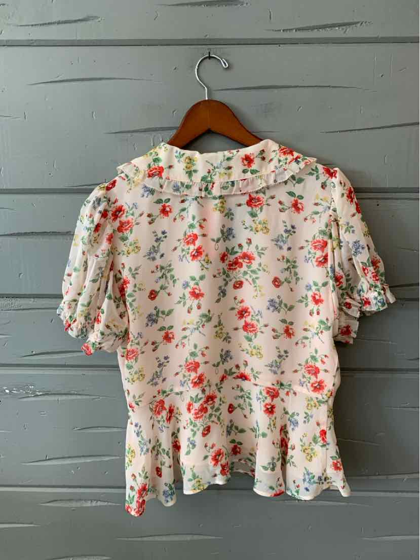 Pink floral blouse with short puff sleeves and a rounded collar, medium size.