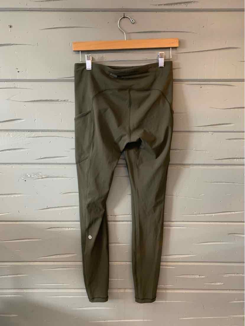 Olive green high-waist leggings with flat seams and a fitted ankle-length cut hanging on a wooden hanger.