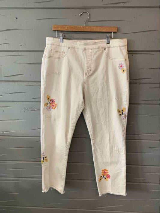 Off-white cropped jeans with colorful floral embroidery and frayed hems.