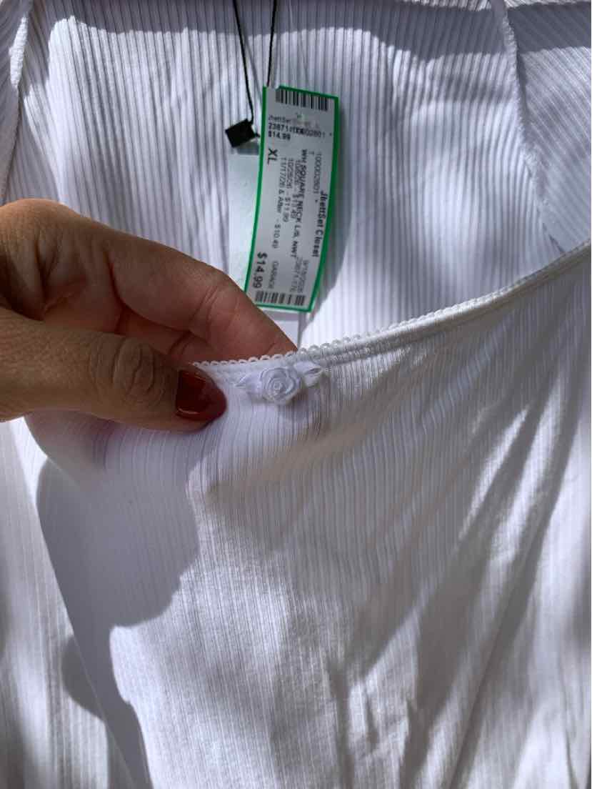 White ribbed fabric garment in size XL with green and white label, close-up on neckline seam and tag.