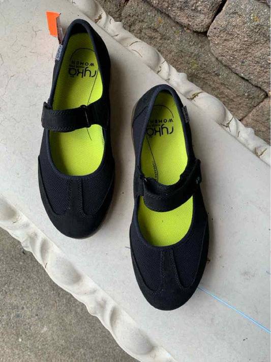 Black Mary Jane-style athletic shoes with adjustable hook-and-loop strap and neon green insoles, size 8.5.