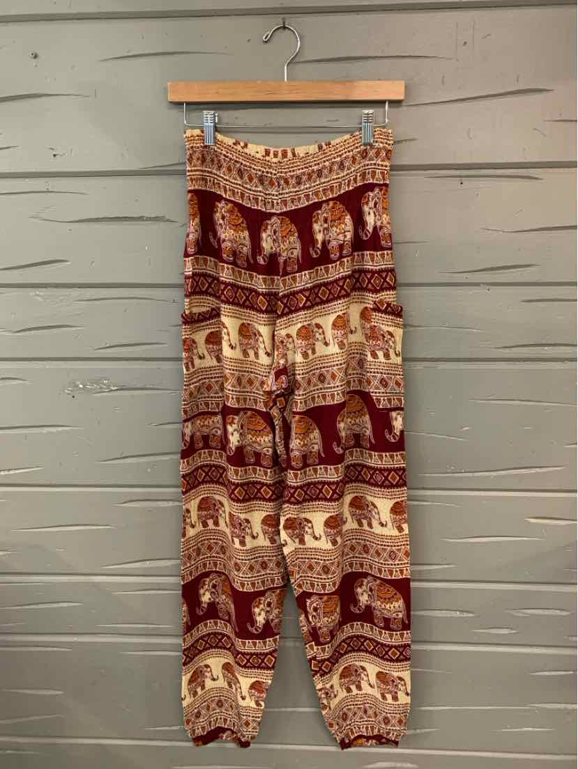 Red elephant-print pants with gathered cuffs and an elastic waistband hanging on a wooden hanger.