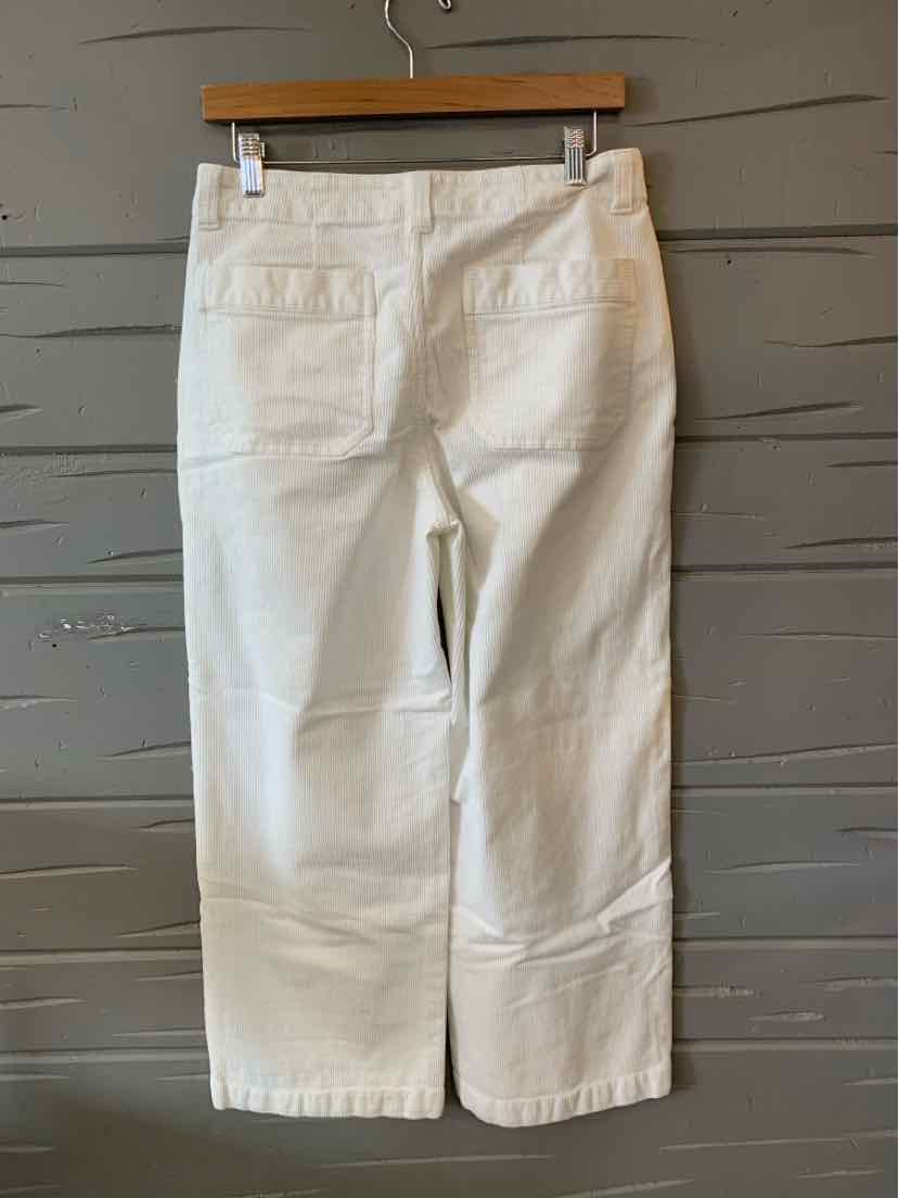 White straight-leg pants with back patch pockets and a mid-rise waist hanging on a wooden hanger.
