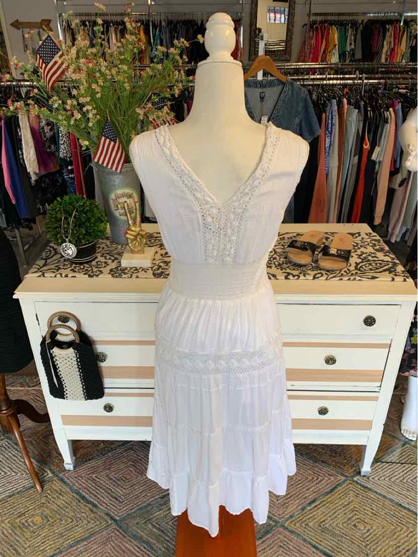 White sleeveless lace dress with V-neck, fitted waist, and layered skirt on mannequin.