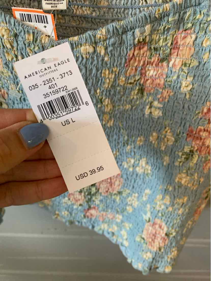 Light blue floral textured fabric with pink and white flowers, held by hand showing price tag.