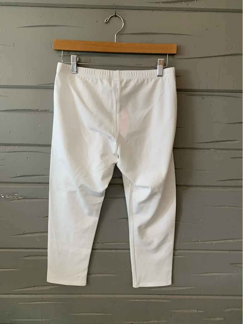 White slim-fit pants with a mid-rise waist and ankle-length cut hanging on a wooden hanger.