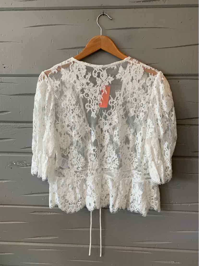 White lace blouse with three-quarter puff sleeves and scalloped hem on wooden hanger.