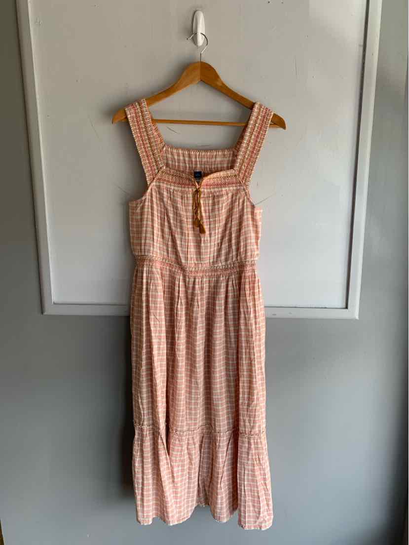 Sleeveless midi dress with peach and white gingham pattern, square neckline, and tiered skirt.