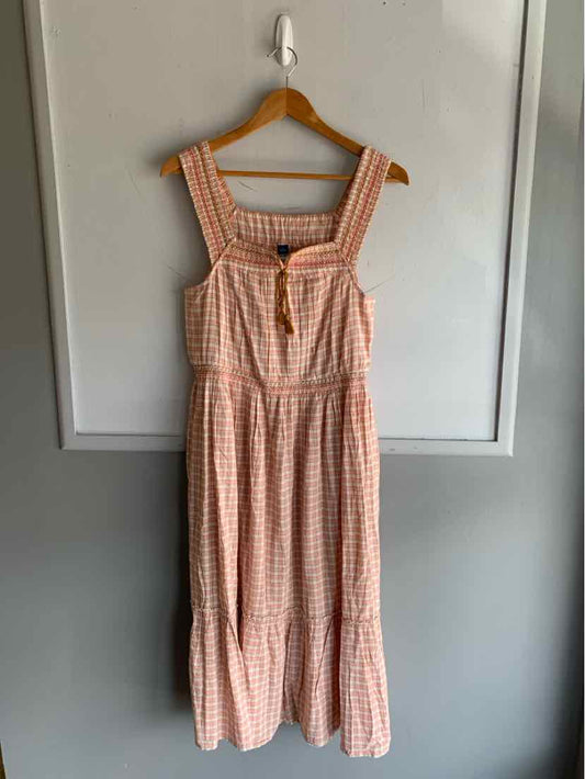 Sleeveless midi dress with peach and white gingham pattern, square neckline, and tiered skirt.