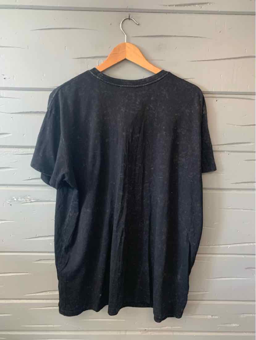 Black oversized short-sleeve T-shirt with crew neck, soft fabric, hanging on wooden hanger.