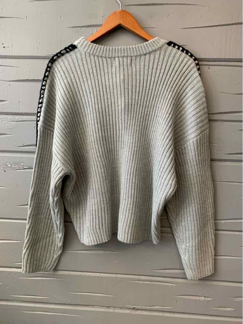Light gray ribbed knit sweater with black and white patterned tape along shoulder seams, long sleeves, crew neck.