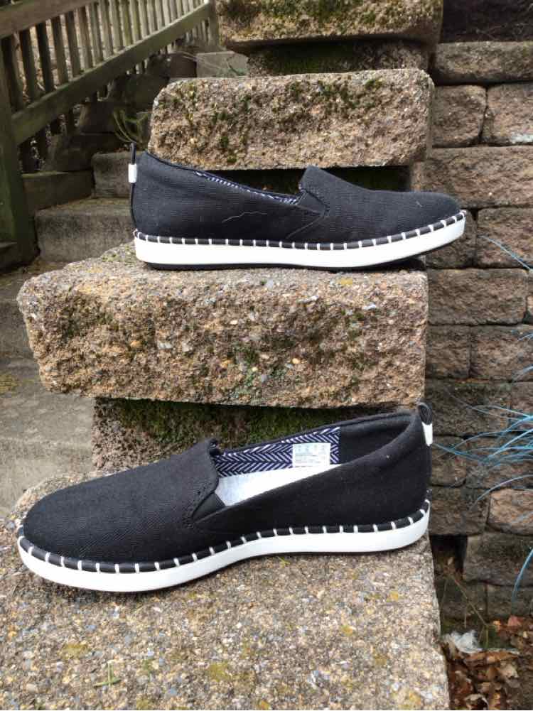 Black slip-on canvas shoes with white rubber soles and textured grips, size 6.5.