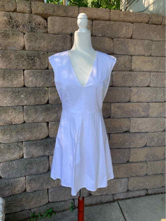White sleeveless dress with deep V-neck and fitted waist, flared skirt, knee-length.