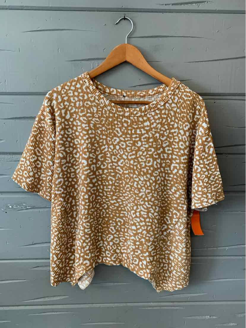 Beige short-sleeve blouse with white cheetah print, round neckline, and loose fit hanging on wooden hanger.