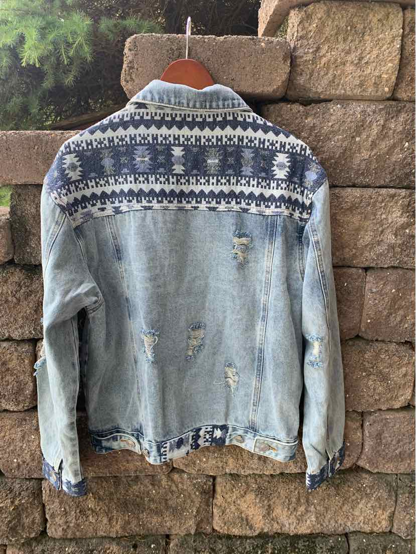 Light blue denim jacket with distressed details and navy fair isle knit pattern across shoulders and cuffs.