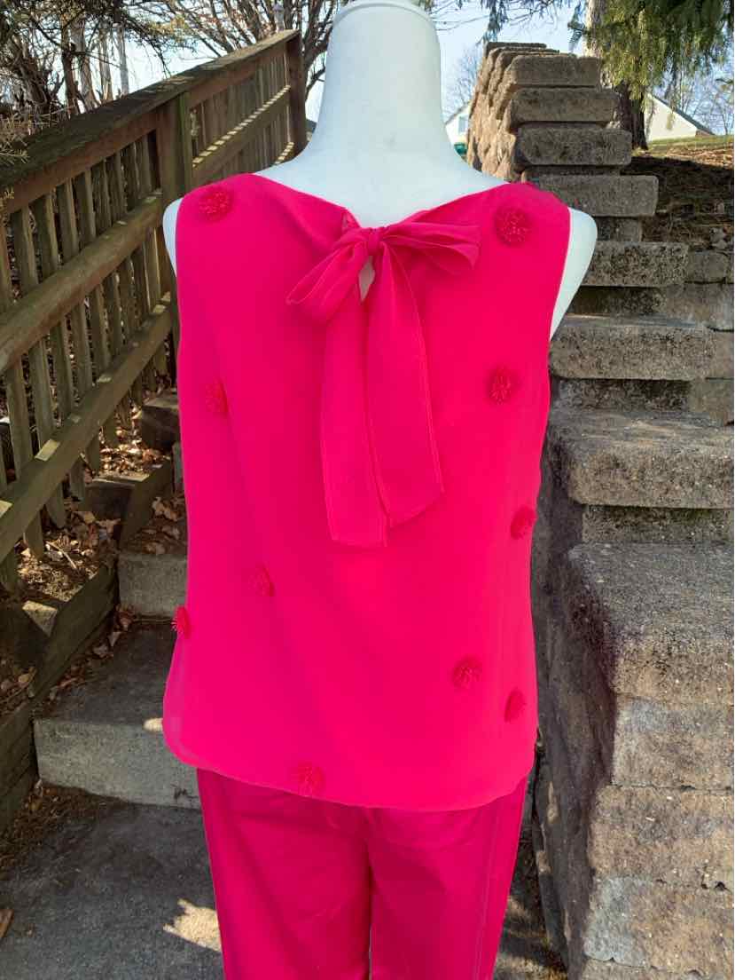 Bright pink sleeveless blouse with bow tie neckline and matching solid pink pants.