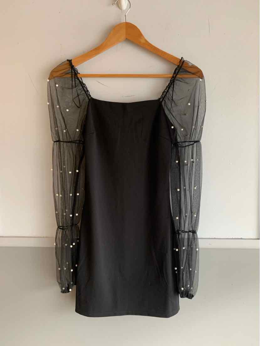 Black mini dress with sheer long puff sleeves adorned with small white pearls.