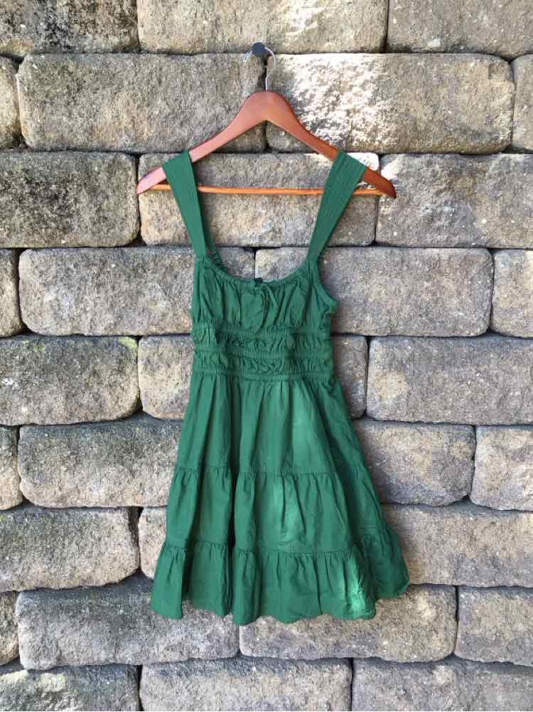 Green sleeveless dress with tiered skirt and wide straps, fitted bodice with gathered waist.