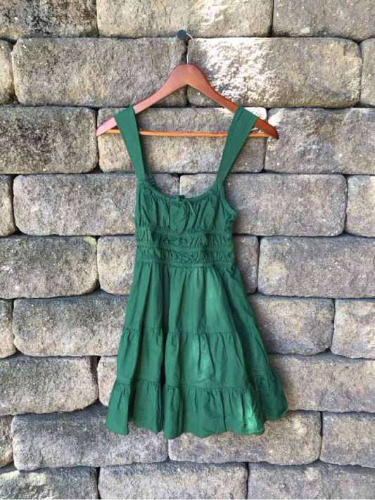 Green sleeveless dress with tiered skirt and wide straps, fitted bodice with gathered waist.