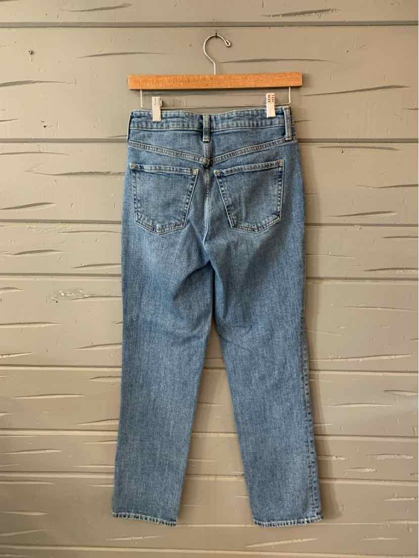 Light blue high-waisted denim jeans with a tapered leg and classic five-pocket design hanging on a wooden hanger.