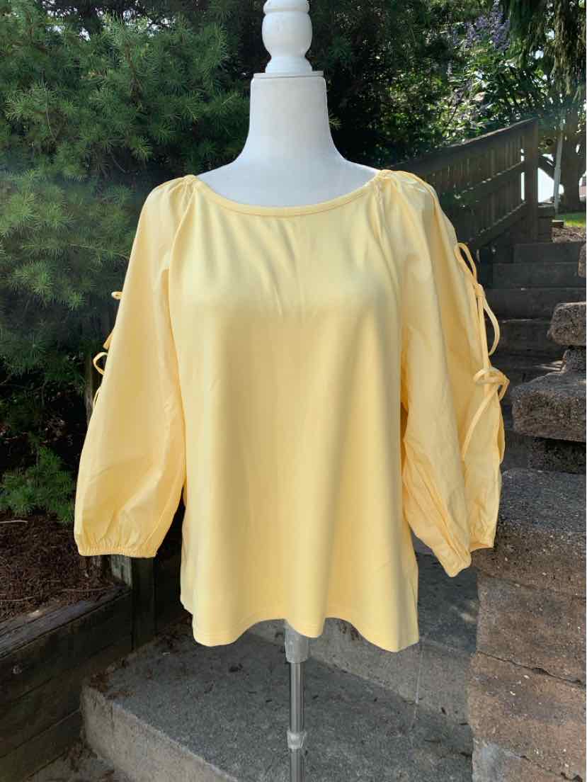 Light yellow long-sleeve blouse with gathered puff sleeves and a loose fit on a white mannequin outdoors.