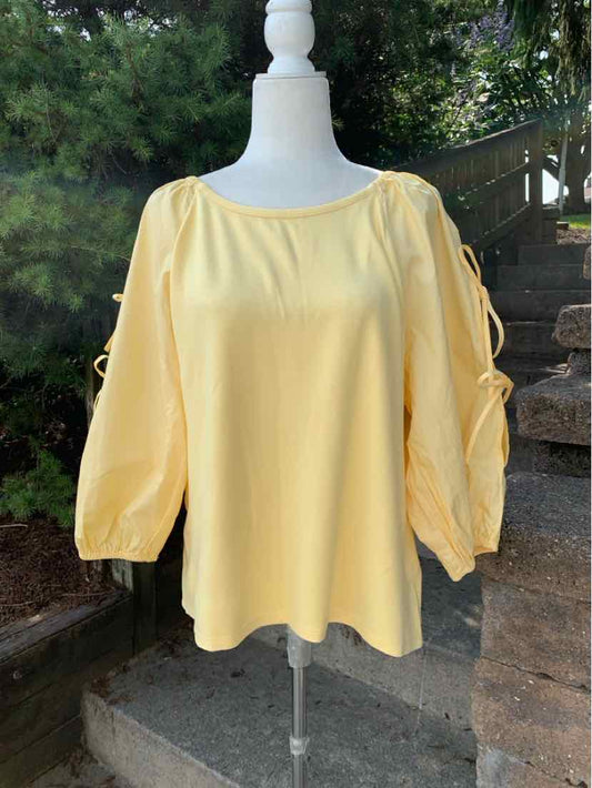 Light yellow long-sleeve blouse with gathered puff sleeves and a loose fit on a white mannequin outdoors.