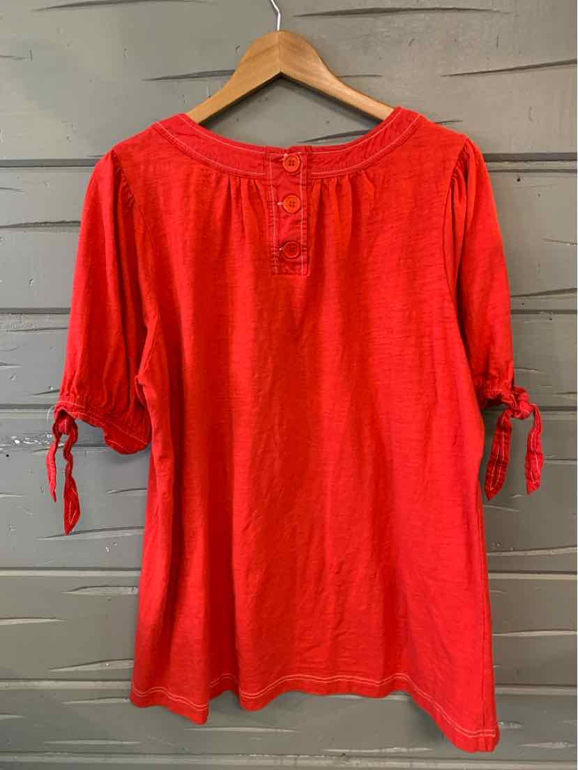 Red long-sleeve blouse with scoop neckline, button details, and tie accents on sleeves.