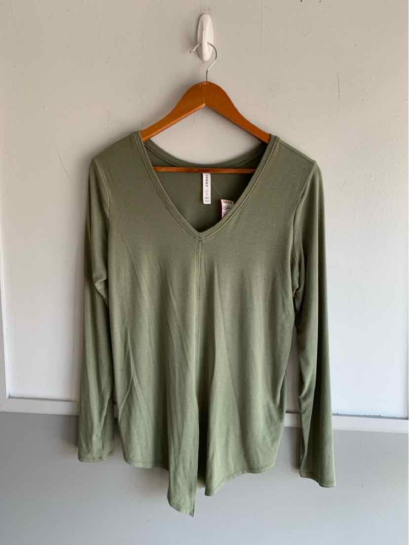 Olive green long-sleeve V-neck top hanging on wooden hanger against white wall.
