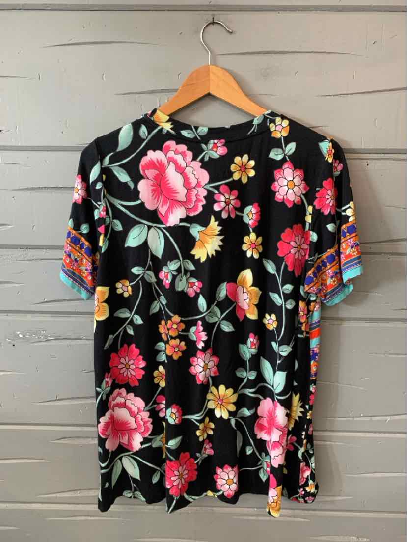 Black short-sleeve shirt with vibrant pink and yellow floral print and colorful patterned sleeve cuffs.